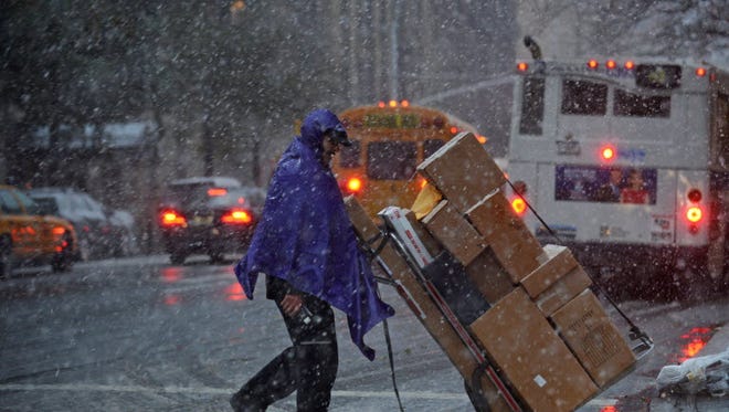 A man makes deliveries while snow falls on Madison Avenue as a strong winter storm hits the northeast  in November 2012 in New York.