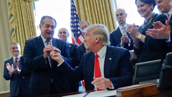 President Trump gives the pen he used to sign an executive order to Dow Chemical CEO Andrew Liveris, as other business leaders applaud in the Oval Office of the White House Feb. 24.
