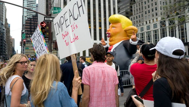 Protesters gather at 59th Street and 5th Ave. in New York near a caricature of President Trump Monday, Aug. 14, 2017, as they protest not far from Trump Tower.