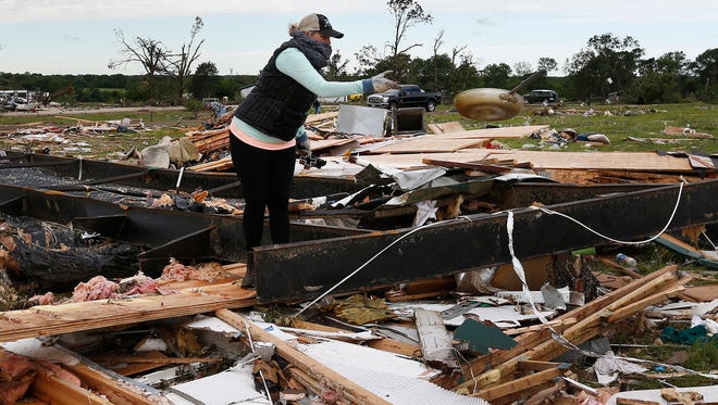 A woman tosses a frying pan out of the rubble, while sifting through the remains of a trailer home that was destroyed when a large tornado hit the area near Canton, Texas on April 30, 2017.