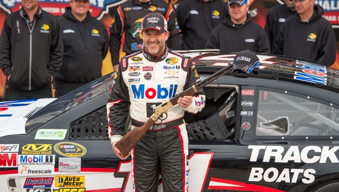Tony Stewart poses with a Texas Motor Speedway rifle after winning the pole for the 2014 Duck Commander 500 in Fort Worth.