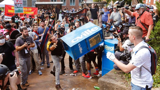White nationalist demonstrators clash with a counter demonstrator  as he throws a newspaper box at the entrance to Lee Park in Charlottesville, Va., Saturday, Aug. 12, 2017. Gov. Terry McAuliffe declared a state of emergency and police dressed in riot gear ordered people to disperse after chaotic violent clashes between white nationalists and counter protestors. (AP Photo/Steve Helber) (AP Photo/Steve Helber)