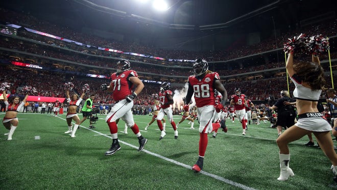 Atlanta Falcons offensive guard Wes Schweitzer (71) and defensive end Takkarist McKinley (98) runs onto the field before their game against the Green Bay Packers at Mercedes-Benz Stadium.
