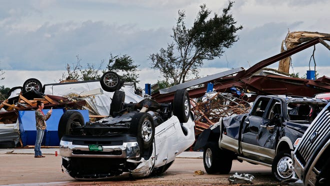 A person takes phone pictures at a local car dealership that was destroyed when a large tornado hit the area near Canton, Texas on April 30, 2017.