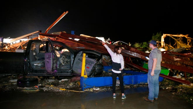 Ernestine Cook of Canton, Texas, points out the damage to spotter Michael Search of Henderson, Texas, as they inspect the damage done to the I-20 Dodge dealership after a tornado hit Canton, Texas on April 29, 2017. Cars and trucks were piled high and the service area was destroyed.