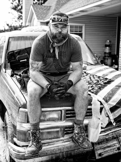 Jeremy Crawford sits on the hood of a truck next to his roommate's flag drying, which was proudly brought home after a tour in Afghanistan. Jeremy, a naval veteran, took on upwards of 5 feet of water. Watson, LA.
