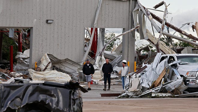 People walk through a local car dealership that was destroyed when a large tornado hit the area near Canton, Texas on  April 30, 2017.