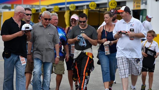 Tony Stewart signs autographs for fans during practice for the 2014 Coke Zero 400 at Daytona International Speedway.
