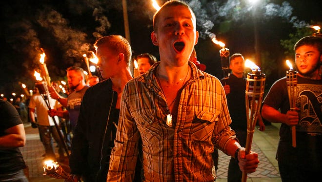 In this photo taken Friday, Aug. 11, 2017, multiple white nationalist groups march with torches through the UVA campus in Charlottesville, Va.   Hundreds of people chanted, threw punches, hurled water bottles and unleashed chemical sprays on each other Saturday after violence erupted at a white nationalist rally in Virginia.  (Mykal McEldowney/The Indianapolis Star via AP)