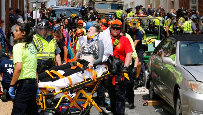 Rescue personnel help injured people after a car ran into a large group of protesters after a white nationalist rally in Charlottesville, Va., Saturday, Aug. 12, 2017. The nationalists were holding the rally to protest plans by the city of Charlottesville to remove a statue of Confederate Gen. Robert E. Lee. There were several hundred protesters marching in a long line when the car drove into a group of them. (AP Photo/Steve Helber)