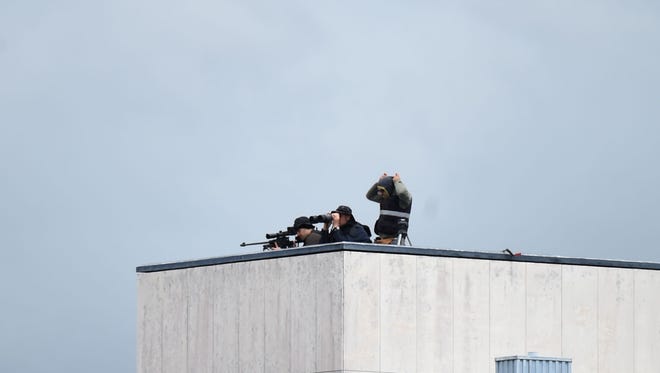 A sniper and his observer watch from a rooftop.