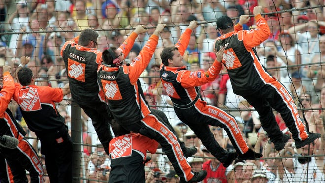 Stewart celebrates his first Brickyard win by climbing the fence at the finish line with his team on Aug. 7, 2005.