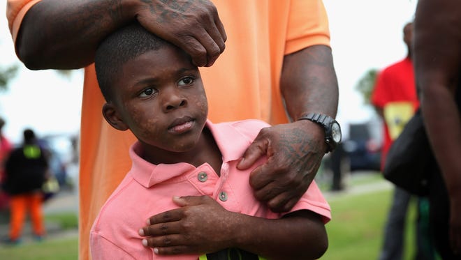 Seven-year-old Terrance Smith II stands with his father during a protest against the George Zimmerman verdict Sunday in Sanford, Fla.